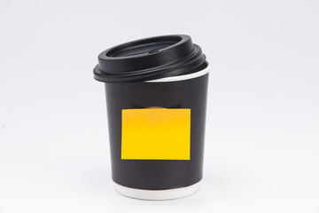 Black plastic paper coffee cup on white take away with yellow post note