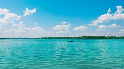 Tropical blue sea with coral reef and blue sky with sun. Bunaken island (Indonesia) on the horizon