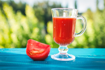 Tomato juice in glass and fresh tomatoes on nature background