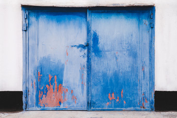 Closed exterior garage doors with old blue and pink paint. Bright abstract background.