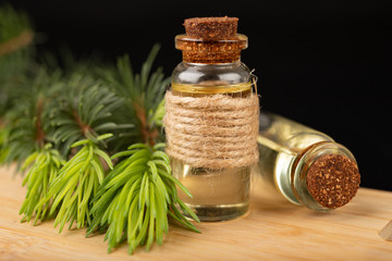 Young shoots of spruce and oil in a glass dish. Ecological preparations on a wooden board.