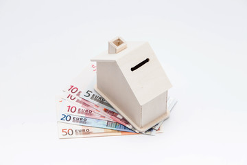 Wooden house coin bank on Euro banknote