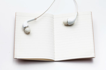 Headphone on blank open notebook on white