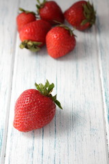 Ripe red strawberry on a white wooden background. 