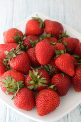 Ripe red strawberry on a white wooden background. 