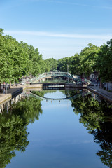 Fototapeta na wymiar Paris, France: Pedestrian bridge over the Canal Saint-Martin with reflection in the water