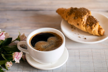Coffee cup and fresh baked croissants on wooden background. Top View.