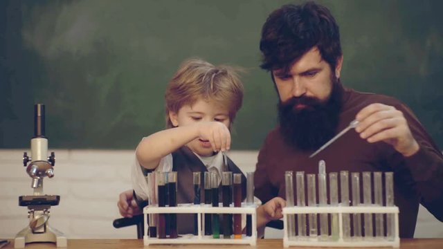 Daddy and his little son Teacher and schoolboy using test tube in class. Man teacher play with preschooler child. Daddy and son together. Back to school and Education concept.