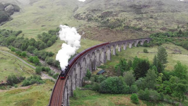 Steam Train crossing the Glenfinnan Viaduct, aerial view by drone - Scotland, UK