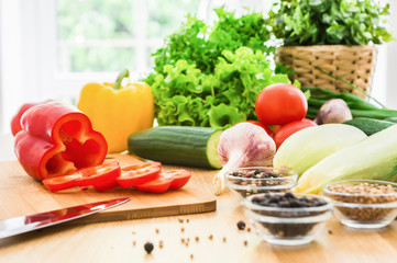 Fresh vegetables and spices on wooden table in front of the window. Summer food.