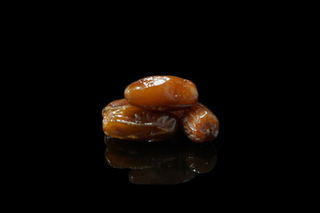 3 dates with reflections on the glass table isolated on black background