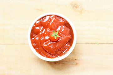 Fresh tomatoes on ketchup in cup tomato sauce on wooden