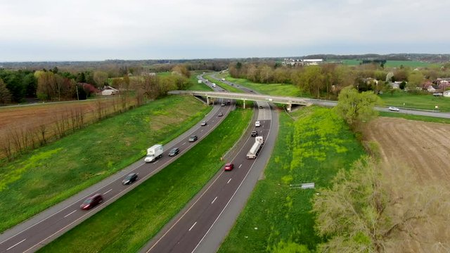 Heavy trucks and cars drive on highway in rural countryside, aerial ascending view of major US four lane road, transportation and travel concept, Pennsylvania state highway 222