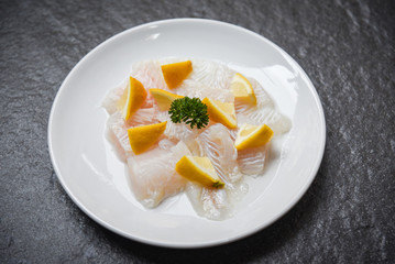 Fresh raw fish fillet piece with lemon on white plate - Close up pangasius dolly fish meat