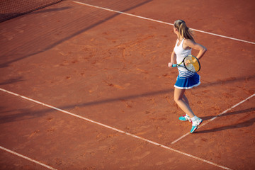 Young woman playing tennis on clay. Forehand.