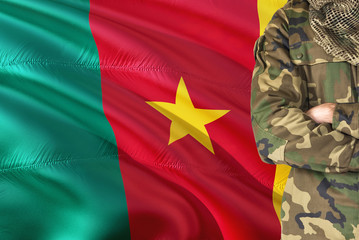 Crossed arms Cameroonian soldier with national waving flag on background - Cameroon Military theme.