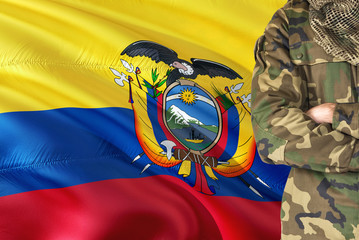 Crossed arms Ecuadorean soldier with national waving flag on background - Ecuador Military theme.