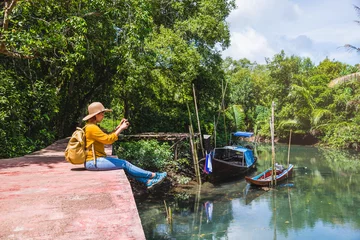 Foto op Canvas Asian woman travel nature. Travel relax. Using Mobile phone Take a boat photo. Sitting and watching the beautiful nature at tha pom-klong-song-nam. Krabi, in Thailand. © last19