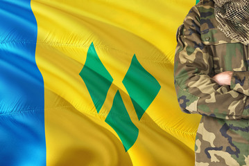 Crossed arms soldier with national waving flag on background - Saint Vincent And The Grenadines...