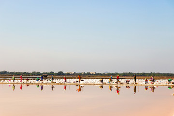 Workers are working with reflection at salt farmin Samut Songkhram,Thailand. Salt production is made from sea water and sunlight until dry into crystal.