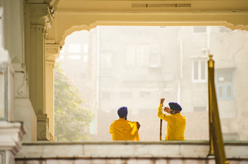 Two security guards wearing a dastar are talking in front of the Harmandir Sahib (Golden Temple) Amritsar, Punjab, India. The Golden Temple is the holiest shrine of the