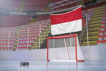 Flag of Monaco in hockey arena with puck and net