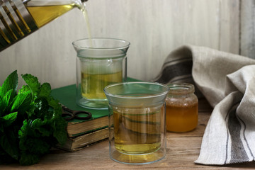 Herbal tea made from mint and lemon balm with honey in glass cups. Rustic style.