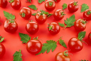 tomato pattern. Fresh ripe red tomatoes set with green leaves on red background.Vegetable natural background.Top view.modern  food backdrop.