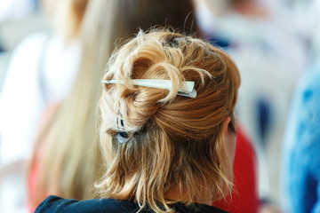 The girl's dyed short hair is bound with an iron barrette. The girl's hair back view.