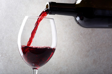 Red wine is poured into a glass from a bottle.
