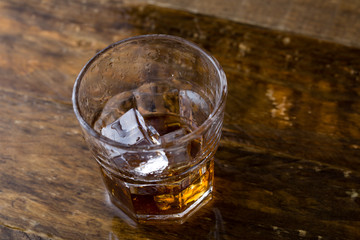 Glass of whiskey on wooden background, close up