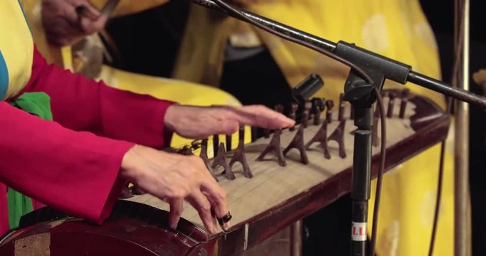 Vietnamese musicians play national ancient instruments in the theater. the musicians are dressed in bright red and yellow clothes. in the frame of the hands of musicians and musical instruments.