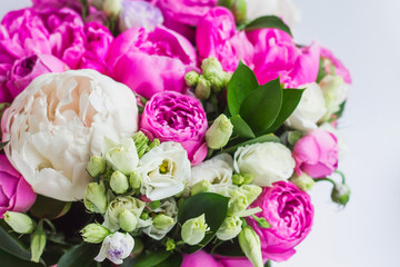 Arrangement of flowers in a hat box. Bouquet of peonies, eustoma, spray rose in a pink box with an oasis on a white background
