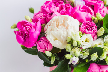 Arrangement of flowers in a hat box. Bouquet of peonies, eustoma, spray rose in a pink box with an oasis on a white background