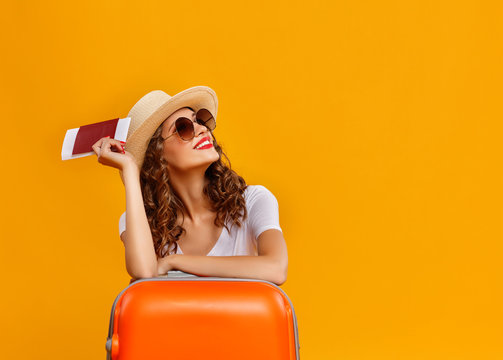 concept of travel. happy woman girl with suitcase and  passport on  yellow background