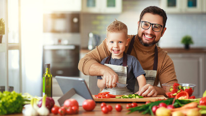 happy family father with son preparing vegetable salad .