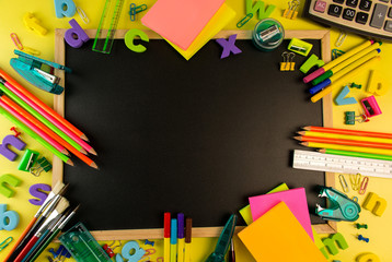 Colorful office and school Stationery items on a black board with back to school typing