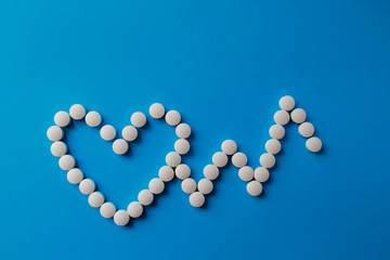 Heap of pills on blue background Assorted pharmaceutical medicine pills, tablets and capsules and bottle on blue background. Copy space for text