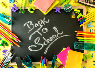 Colorful School supplies back to school concept stationery item on a black board
