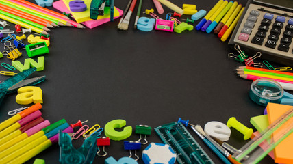 Office and school stationery items on a black board