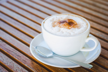 close up modern hot coffee with coffee bubble foam pattern and texture in white cup looking and feel so delicious on wood table in coffee shop.