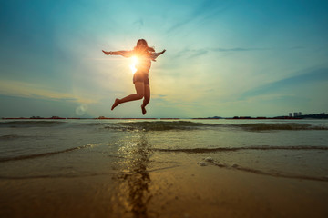 Fototapeta na wymiar freedom asian beautiful woman happiness jump and dance with sunset beach background
