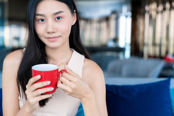 asian woman in casual working dress take a break with coffee and magazine on sofa in living room home background