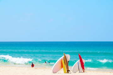 Surfboard on sand tropical beach with sea wave and blue sky background. Summer vacation background concept. - Image