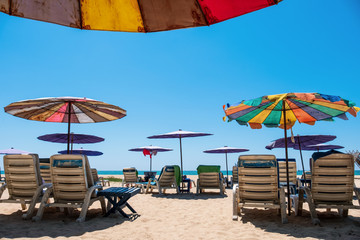 Sunbeds and umbrellas on tropical beach with blue sky. Sands and sea view, Summer background - Image