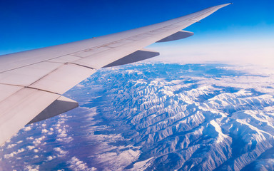 Fototapeta na wymiar Aerial view of Taurus Mountains covered with snow. Airplane right wing while flying seen through window of passenger aircraft. Flying at 35000 feet over ground. Travel concept - Image.