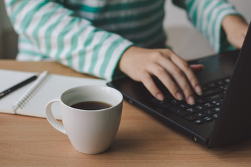 Cup of coffee with businesswoman working with laptop on desk office.
