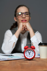 Business woman sitting to table with red alarm clock