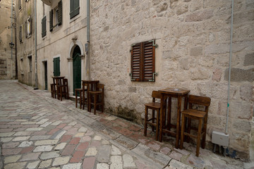 Fototapeta na wymiar The narrow streets of the old town of Kotor with high chairs on the street.