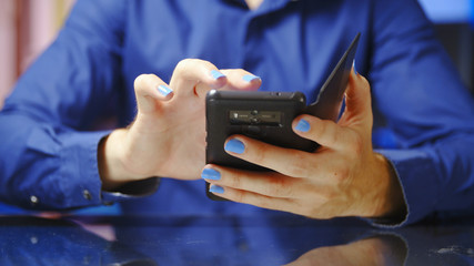 Male person with long blue fingernails use smartphone